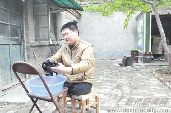 吴洪飞坐在凳子上洗衣服。记者 李静 摄