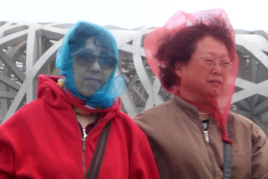 4月17日,北京出现大风沙尘天气.游客用纱巾包裹头部躲避沙尘.